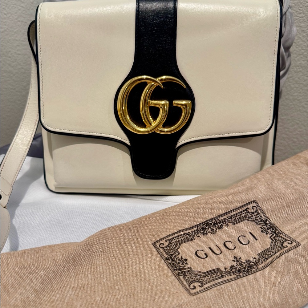 Gucci Arli leather white and black adjustable crossbody with GG gold logo.
